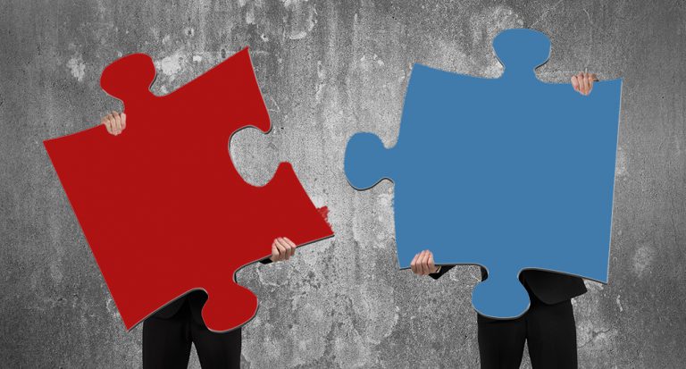 Two people holding red and blue jigsaw pieces that fit together