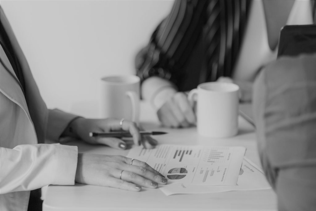 Colleagues with coffee mugs reviewing charts at a meeting