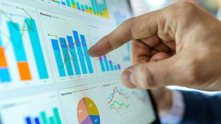 Une main désigne des graphiques financiers sur un écran
