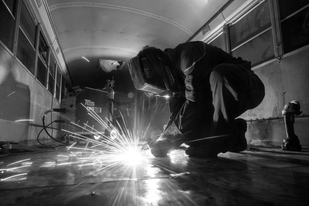 A welder crouching at work, sparks flying