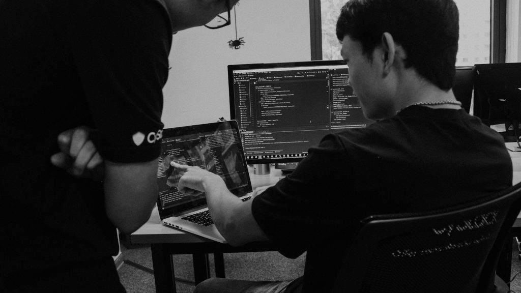 Developers working on laptops and a screen of code