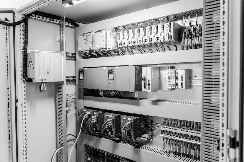 An open industrial electrical control cabinet with wiring and modules