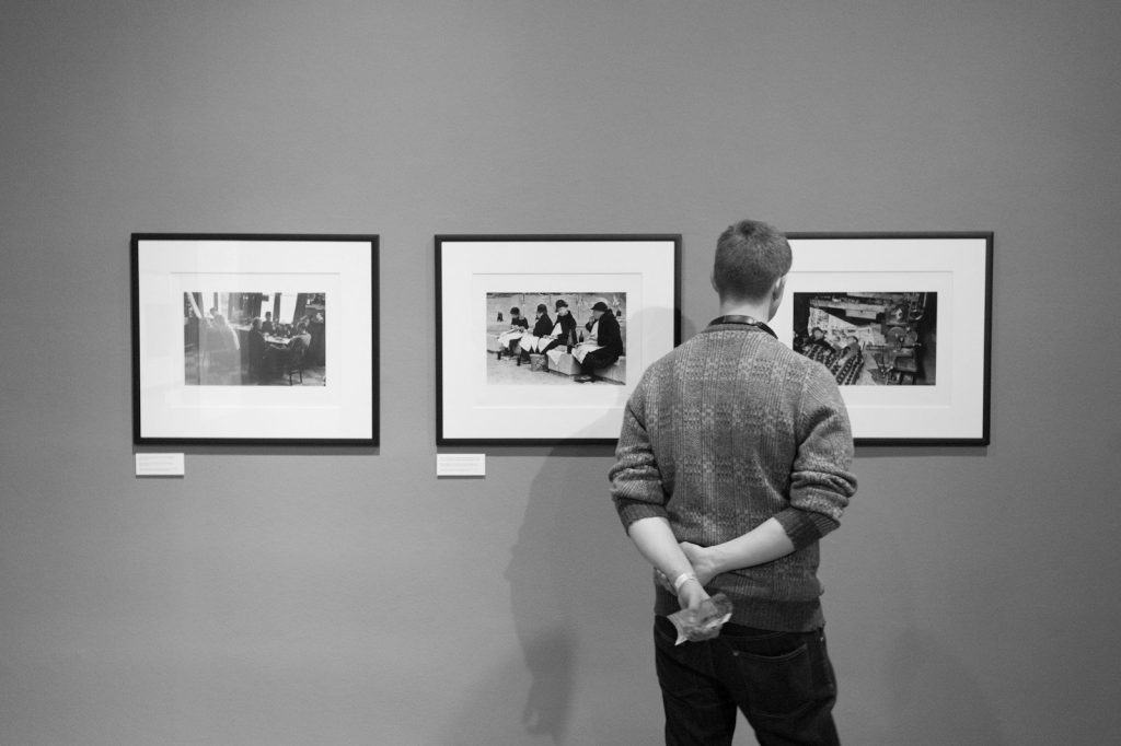 A man looking at framed photographs in a gallery